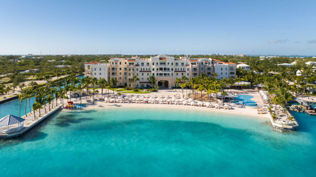 Drone aerial view of Blue Haven's private beach with clear turquoise water, sea kayaks, beach chairs and beachfront pool with swim-up bar.